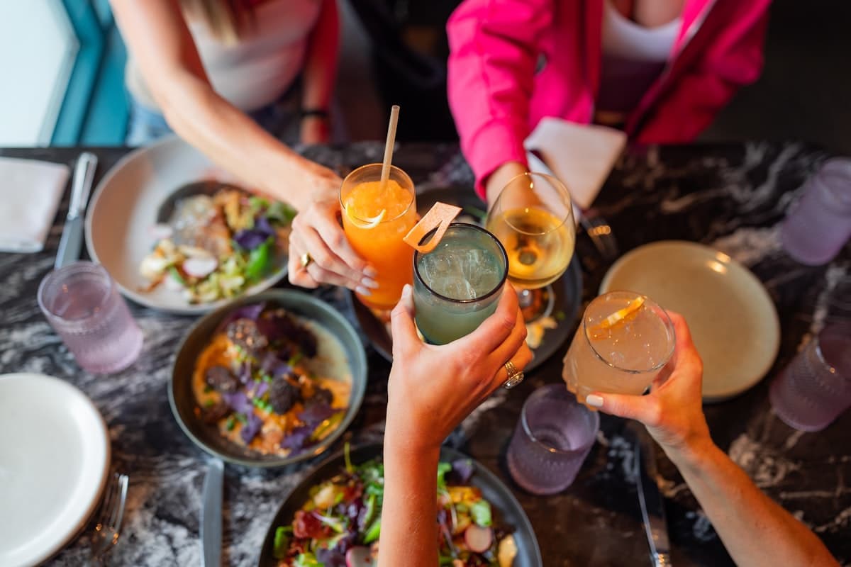 Friends clinking glasses and sharing updates at a summer meal.